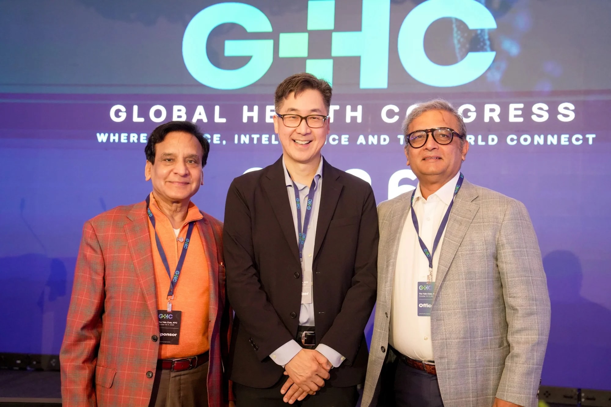 Three attendees in front of the Congress stage screen
